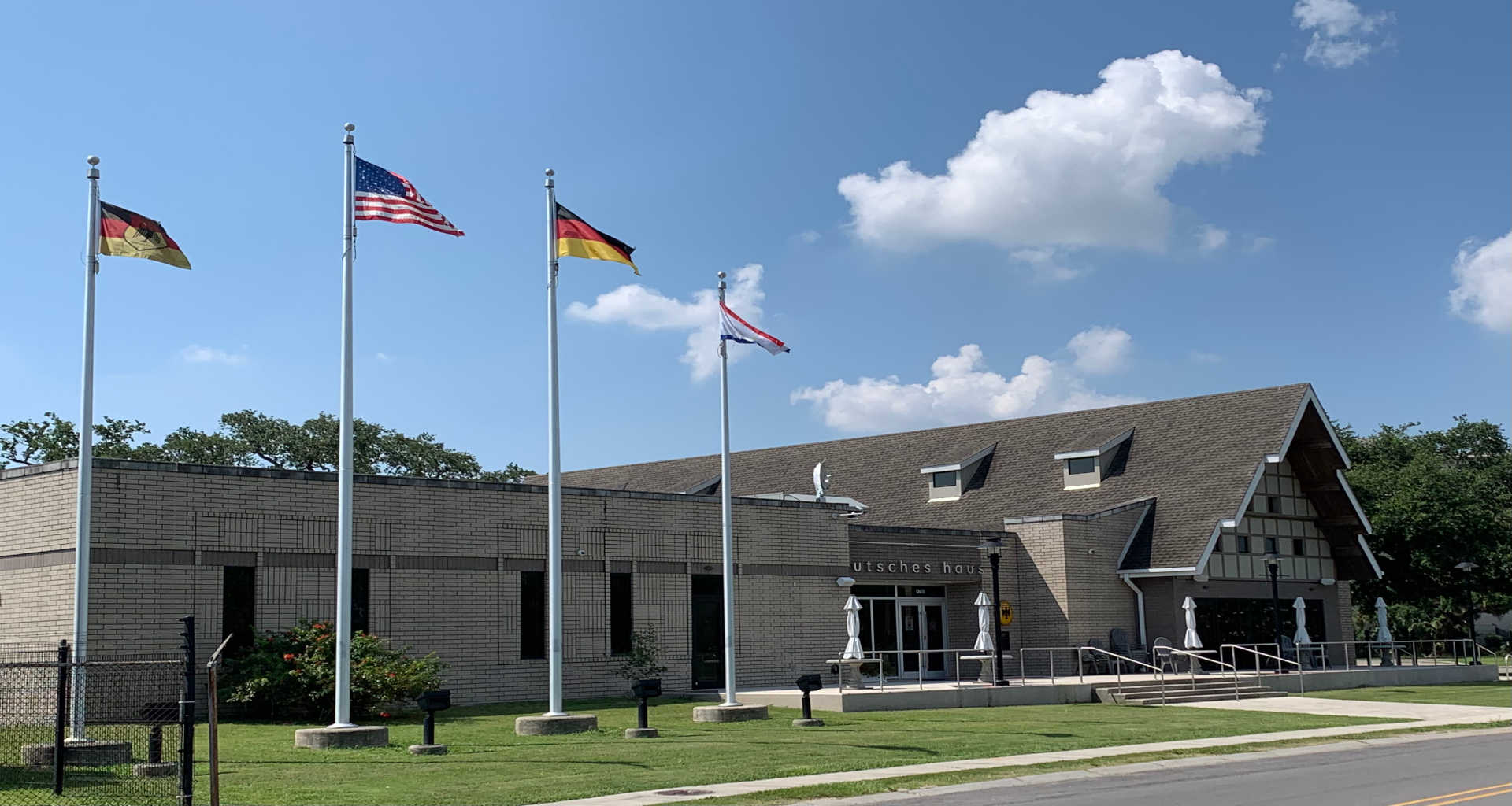 50DHFront1920x1024 Daytime front view of Deutsches Haus New Orleans with flags.